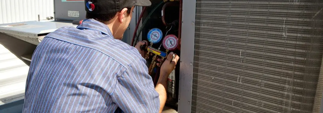 HVAC technician servicing a condenser unit in Blue Springs